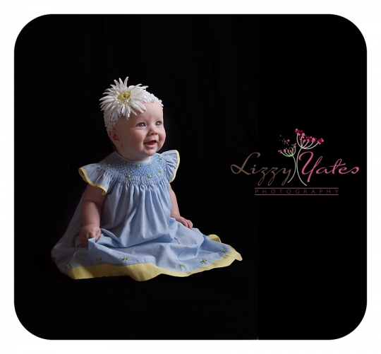6 month old girl smiles in her blue dress during a West Little Rock family photography session