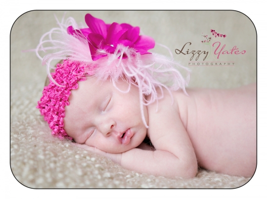 A newborn baby girl sleeping and wearing a pink headband during her pictures in Little Rock Arkansas 